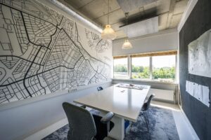 Vergaderruimte met een grote wandkaart van een stadsplattegrond aan de Anthony Fokkerweg en een tafel met stoelen bij een raam met uitzicht op groen.